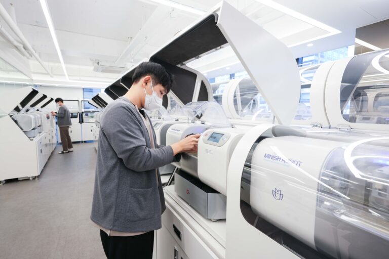A dental technician using a MINISH ROBOT milling machine for precision veneer production.
