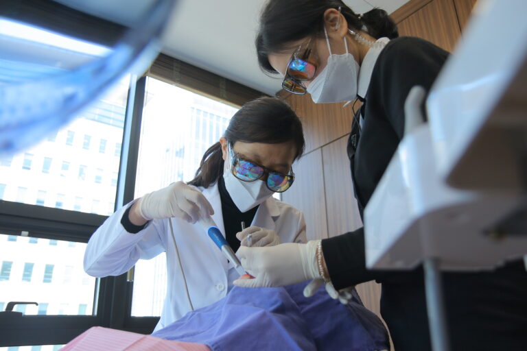 Two MINISH dental specialists in protective gear performing a precision tooth preparation using advanced dental tools for minimal-precision veneers.