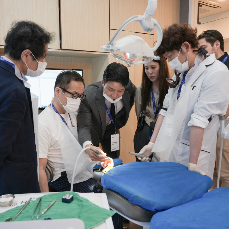 Dentists practicing on a large tooth model during hands-on training