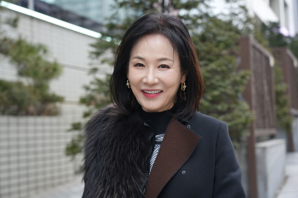 A mature woman in a black fur coat smiling after a restorative MINISH treatment for chipped or worn teeth.